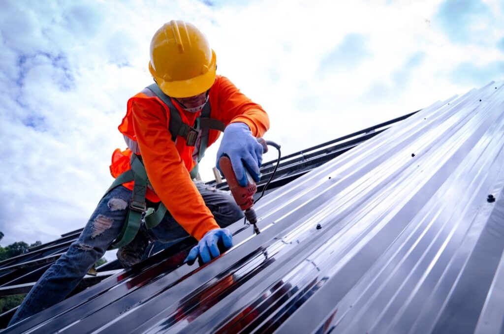 stock-photo-roofer-working-on-roof-structure-of-building-on-construction-site-roofer-using-air-or-pneumatic-1538826422-transformed-min