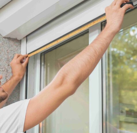 A man carefully measuring window to fit the window frame with precision and focus.