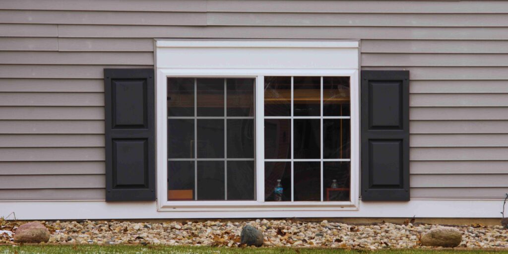 A house window adorned with black shutters, enhancing its classic architectural appeal.