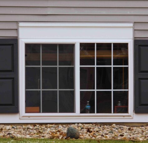 A house window adorned with black shutters, enhancing its classic architectural appeal.