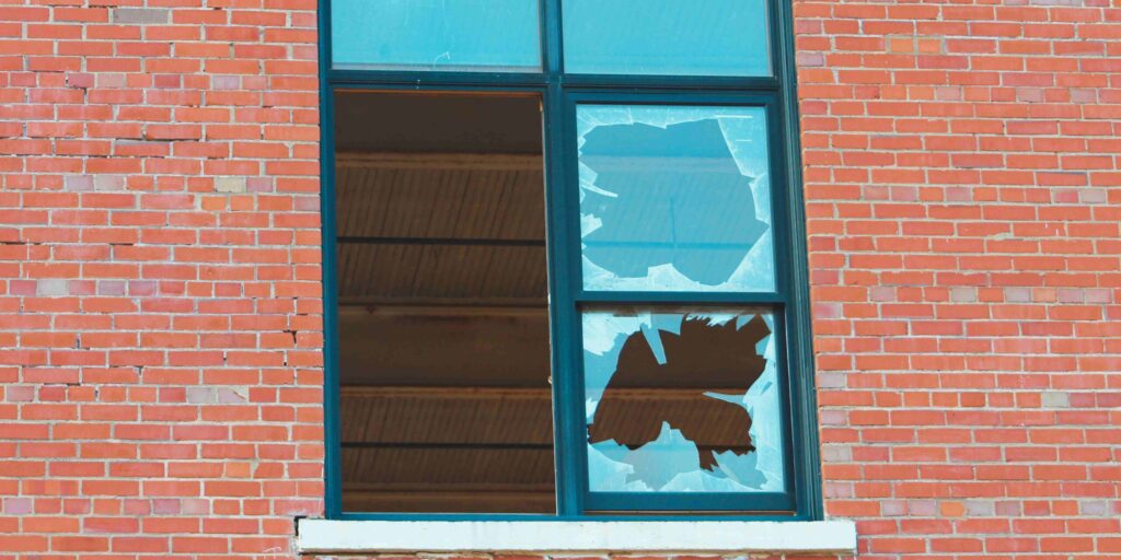 A window featuring a broken pane of glass, highlighting the damage and vulnerability of the structure.